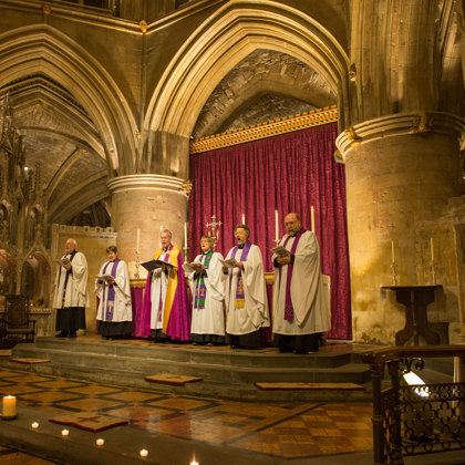Four people delivering a service dressed in religious clothes in Tewkesbury Abbey