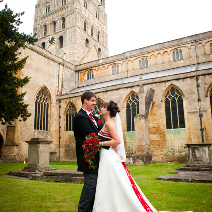A couple getting married showing in wedding dress in front of Tewkesbury Abbey