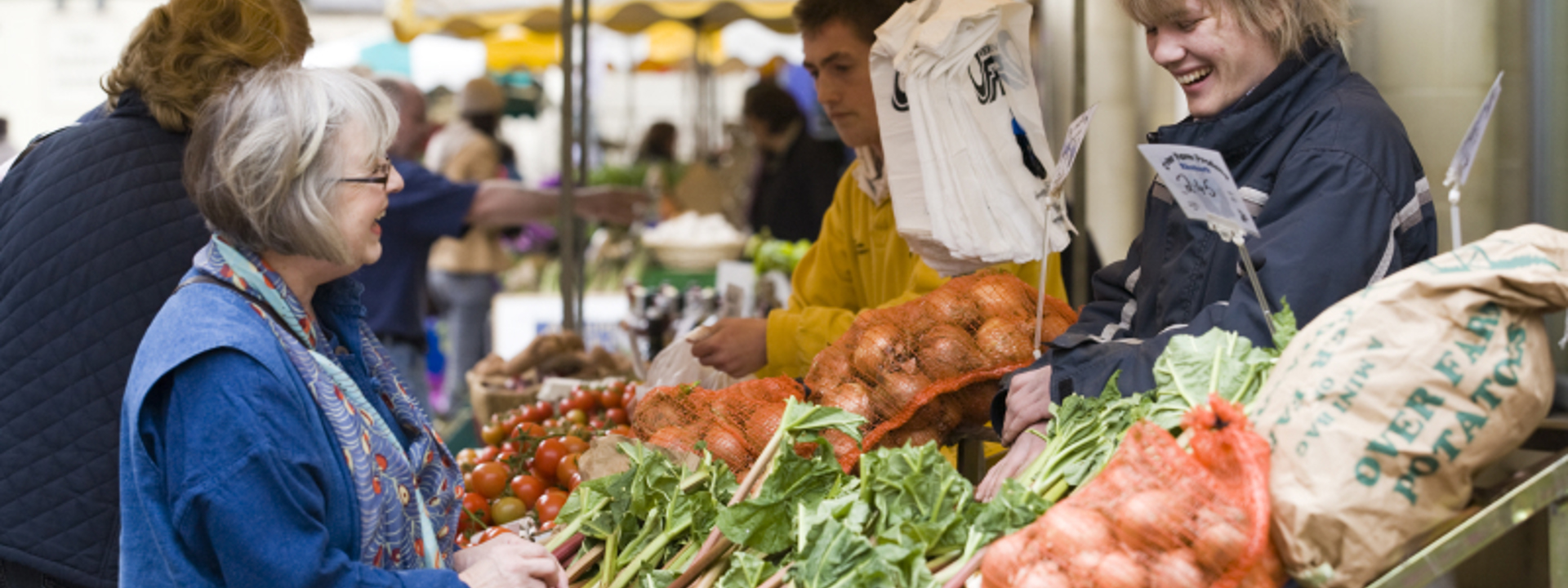 two people chatting over a fruit and veg stall 