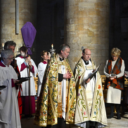 A religious ceremony at Tewkesbury Abbey a handful of people in the Abbey wearing religious dress. 